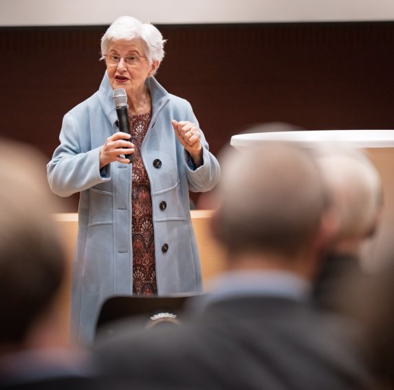 Ehrengast Lili Keller-Rosenberg spricht am Mikrofon zu den vor ihr sitzenden Besuchern.